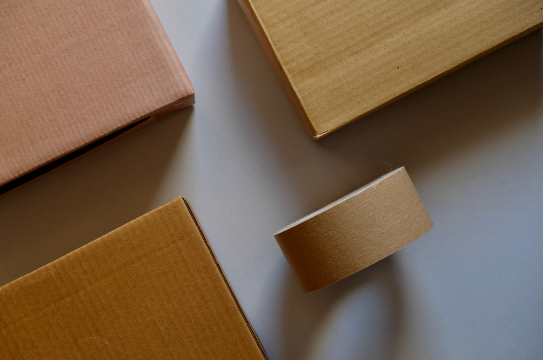 An image of various sized kraft shipping boxes and a roll of packing tape to highlight the packaging journey of organic bean company, beanstory